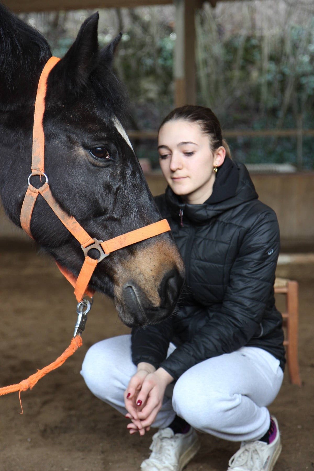 Una partecipante accovacciata accanto a un cavallo al termine di un workshop