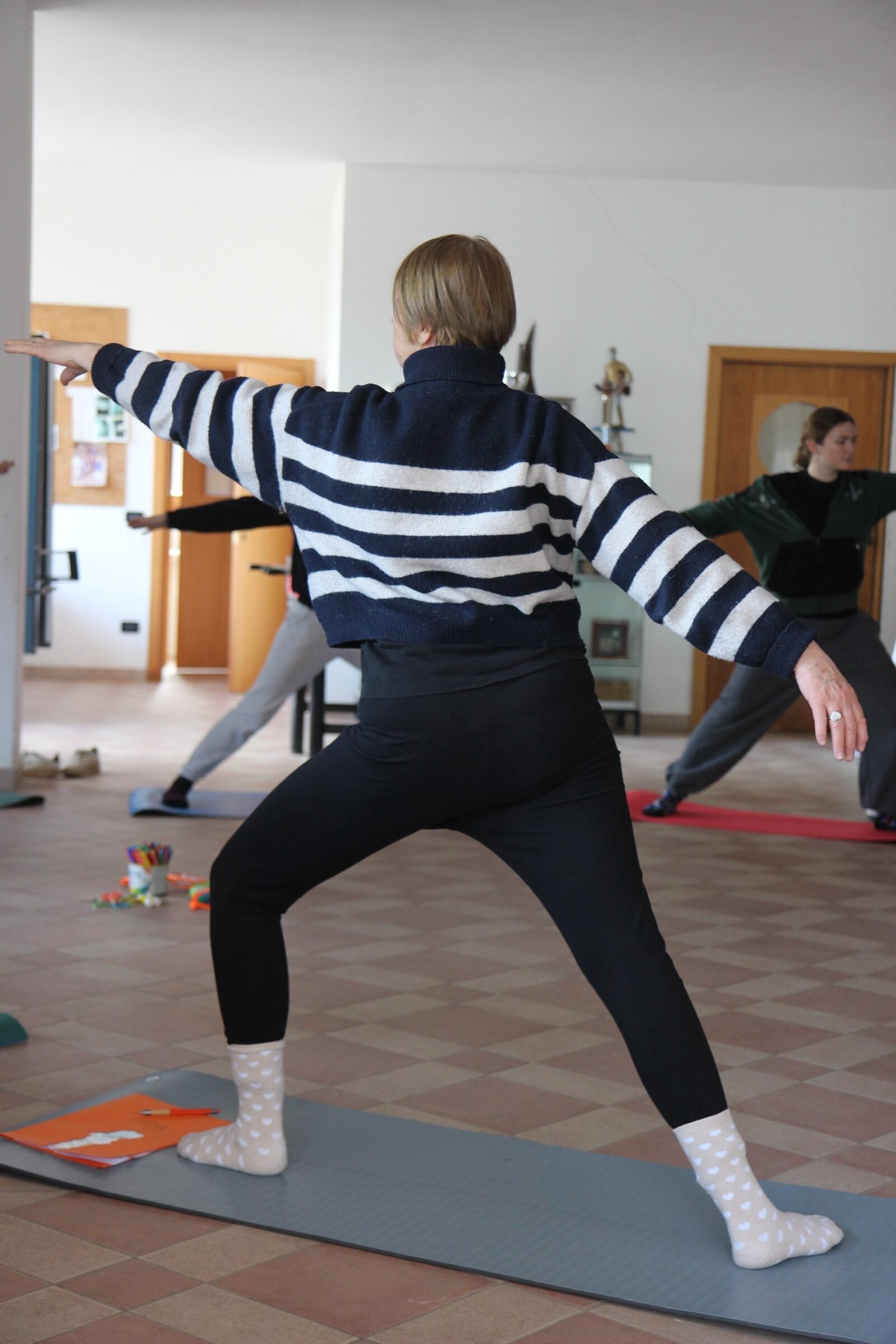 Un gruppo in posizione del guerriero durante una sessione di Yoga della Risata