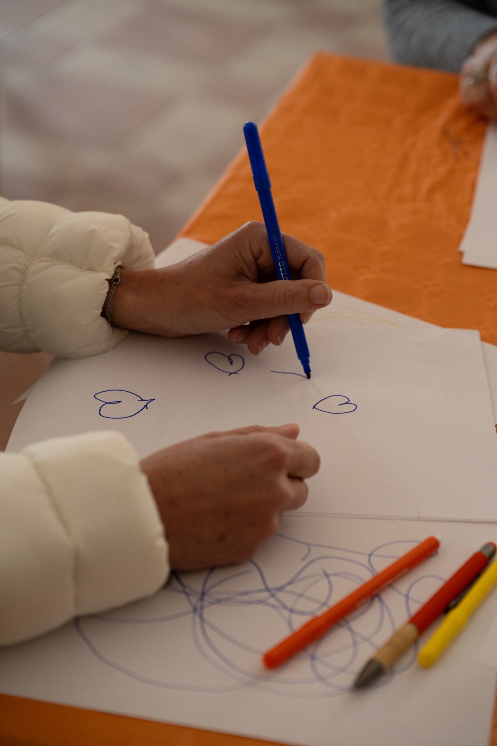 Mani che disegnano dei cuori su un foglio