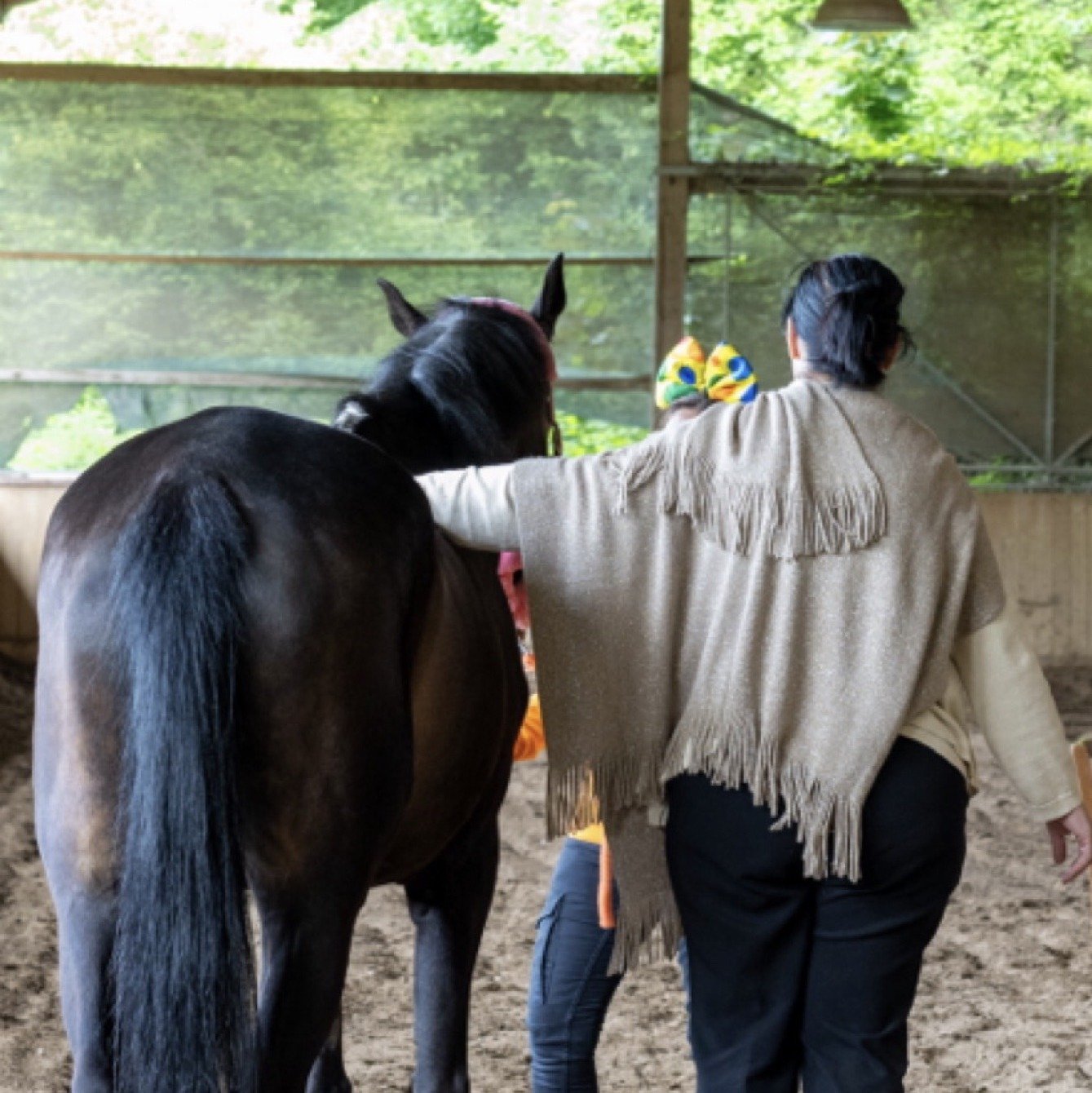 Una partecipante ripresa di spalle vicino a un cavallo